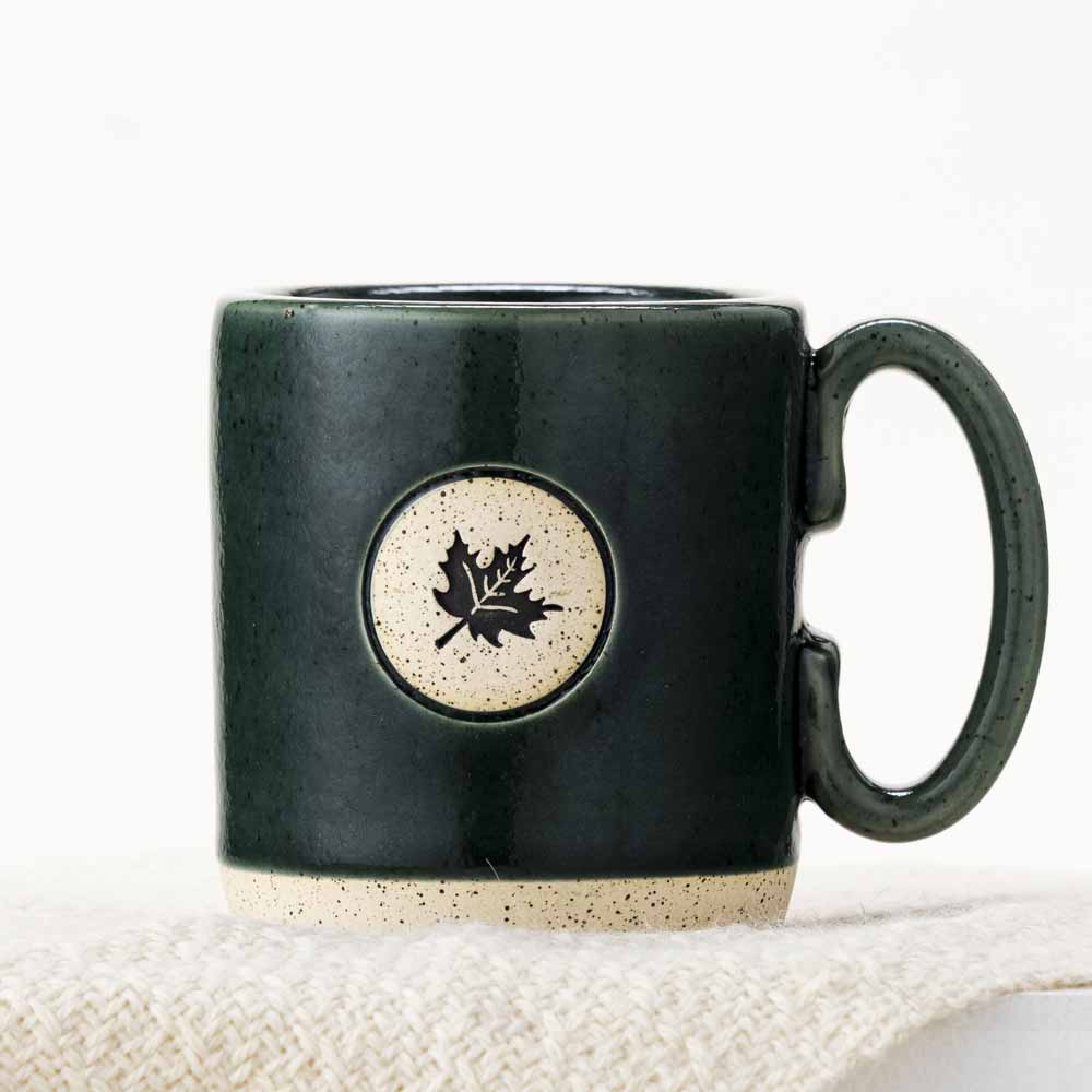 Dark green stoneware mug with maple leaf design