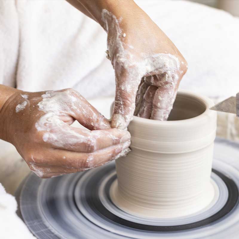 hands throwing a mug on a pottery wheel